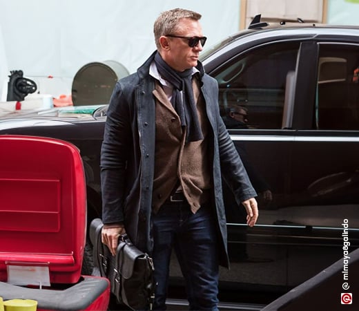 Daniel Craig wearing a sweater with a leather jacket and scarf