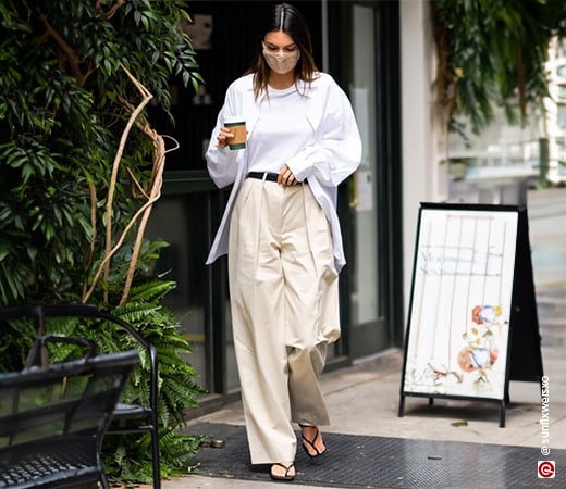 Kendall Jenner in a white shirt paired with pleated beige trousers