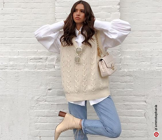 Woman wearing a yellow sweater vest with baggy jeans