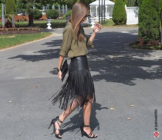 Woman wearing black leather fringed skirt with green top