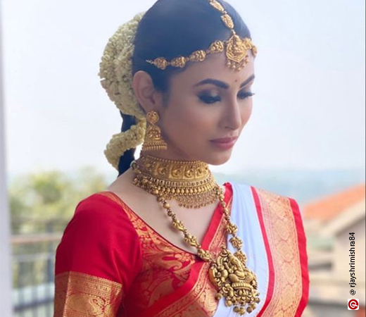 Mouni Roy wearing a red and white saree with temple jewellery 