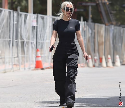 Kim Kardashian in a black form-fitting t-shirt and black cargo pants.
