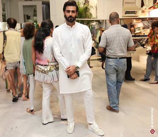 Man wearing a white kurta and pajama with white and gold studded sneakers