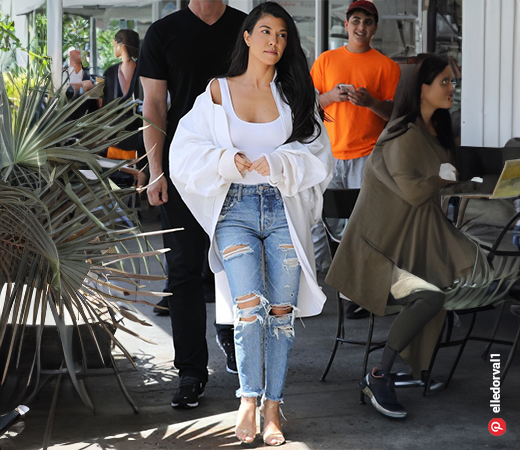 Kourtney Kardashian wearing a bodysuit with ripped jeans