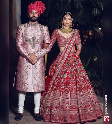 bride wearing red and holding hands with the groom
