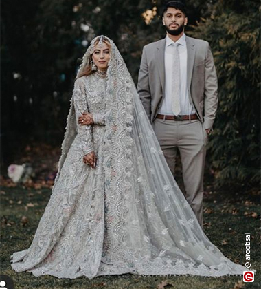 bride and groom standing against a garden background
