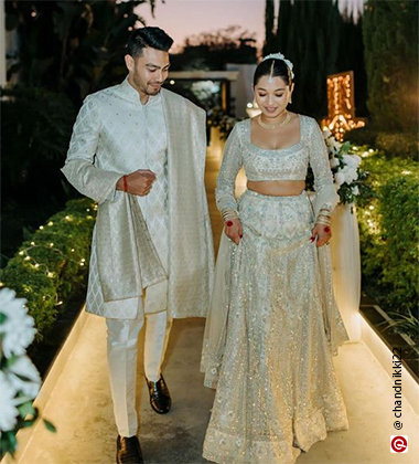 bride and groom walking in white outfits
